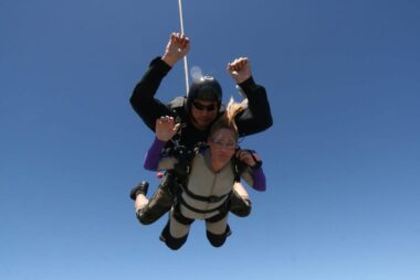 A woman is shown going skydiving with her instructor.